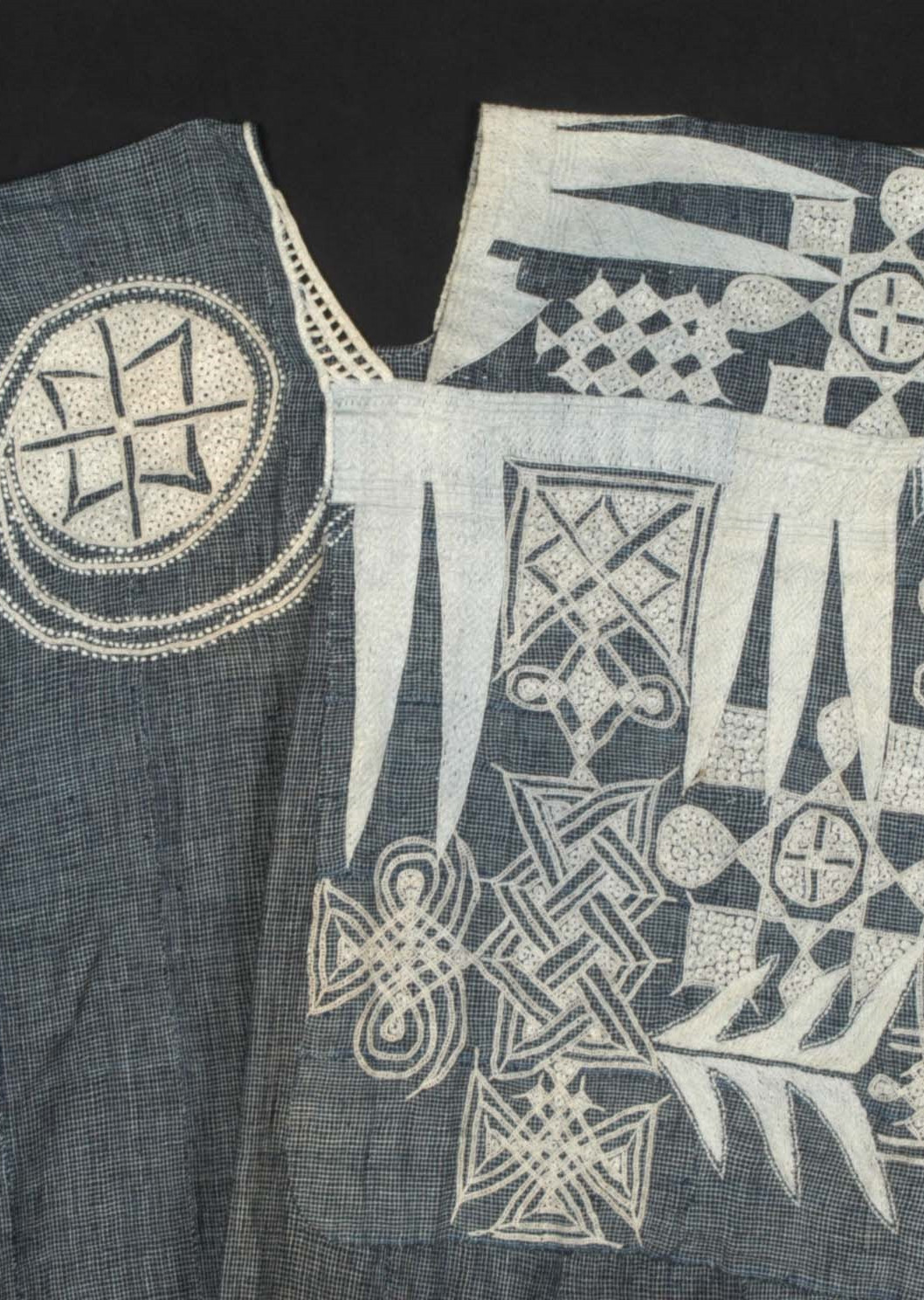 Blauwe katoenen boubou uit het begin van de 20e eeuw, Nigeria. De halslijn en de voorzak zijn versierd met een gedetailleerd wit borduursel met abstracte motieven. (TM-2770-1)