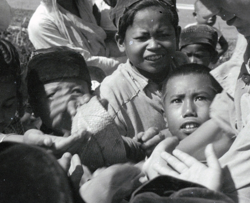 Uitdelende Nederlandse militair omringd door kinderhanden tijdens de feestelijkheden in Cipanas (Java) © Erven C.J. Taillie