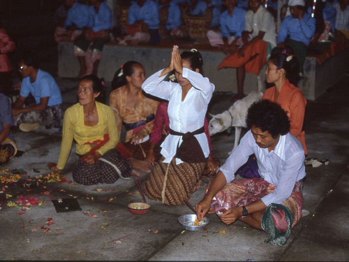 Een vrouw in een witte kebaya biedt haar offers aan de goden aan door middel van gebed. In de gebeden wordt meestal gevraagd om welzijn en voorspoed voor jezelf en familie. Haar witte kebaya vormt een uitzondering. 24 mei 1983. (7358-76) © Francine Brinkgreve