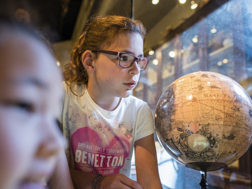 Meisje bekijkt object in Wereldmuseum Leiden tijdens het schoolprogramma Geloven in de wereld